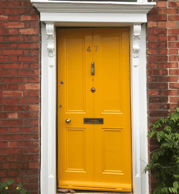 External after painting photo of a Yellow front door with white white moulding by Cornelius Green Decorators