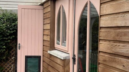 External baby pink and natural wood cottage shed extension with wood and metal fencing - before image.
