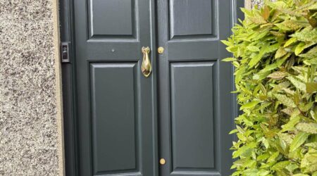 Exterior after painting photo of a dark green front door with gold fixtures by Cornelius Green Decorators