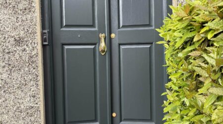 Exterior after painting photo of a dark green front door with gold fixtures by Cornelius Green Decorators