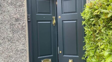 Exterior after painting photo of a dark green front door with gold fixtures by Cornelius Green Decorators