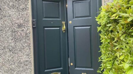 Exterior after painting photo of a dark green front door with gold fixtures by Cornelius Green Decorators